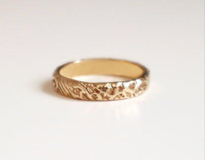 Gold ring with a textured band on a light gray background