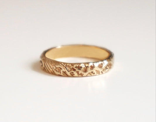 Gold ring with a textured band on a light gray background