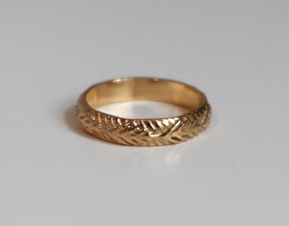 Gold ring with intricate design on a light gray background