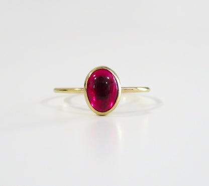 Gold ring with a red gemstone on a white background