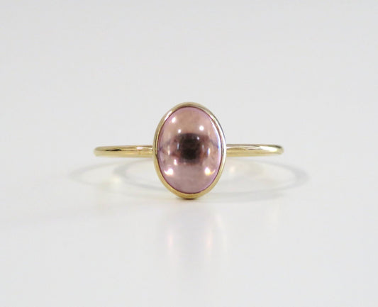 Gold ring with a pink gemstone on a white background