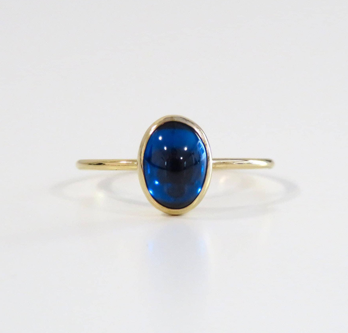 Gold ring with a blue gemstone on a white background