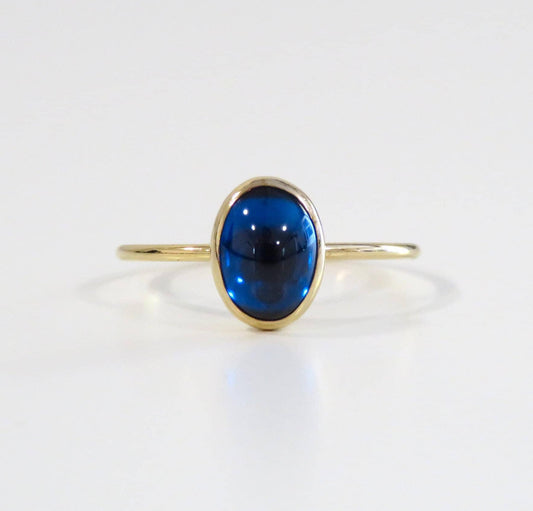 Gold ring with a blue gemstone on a white background