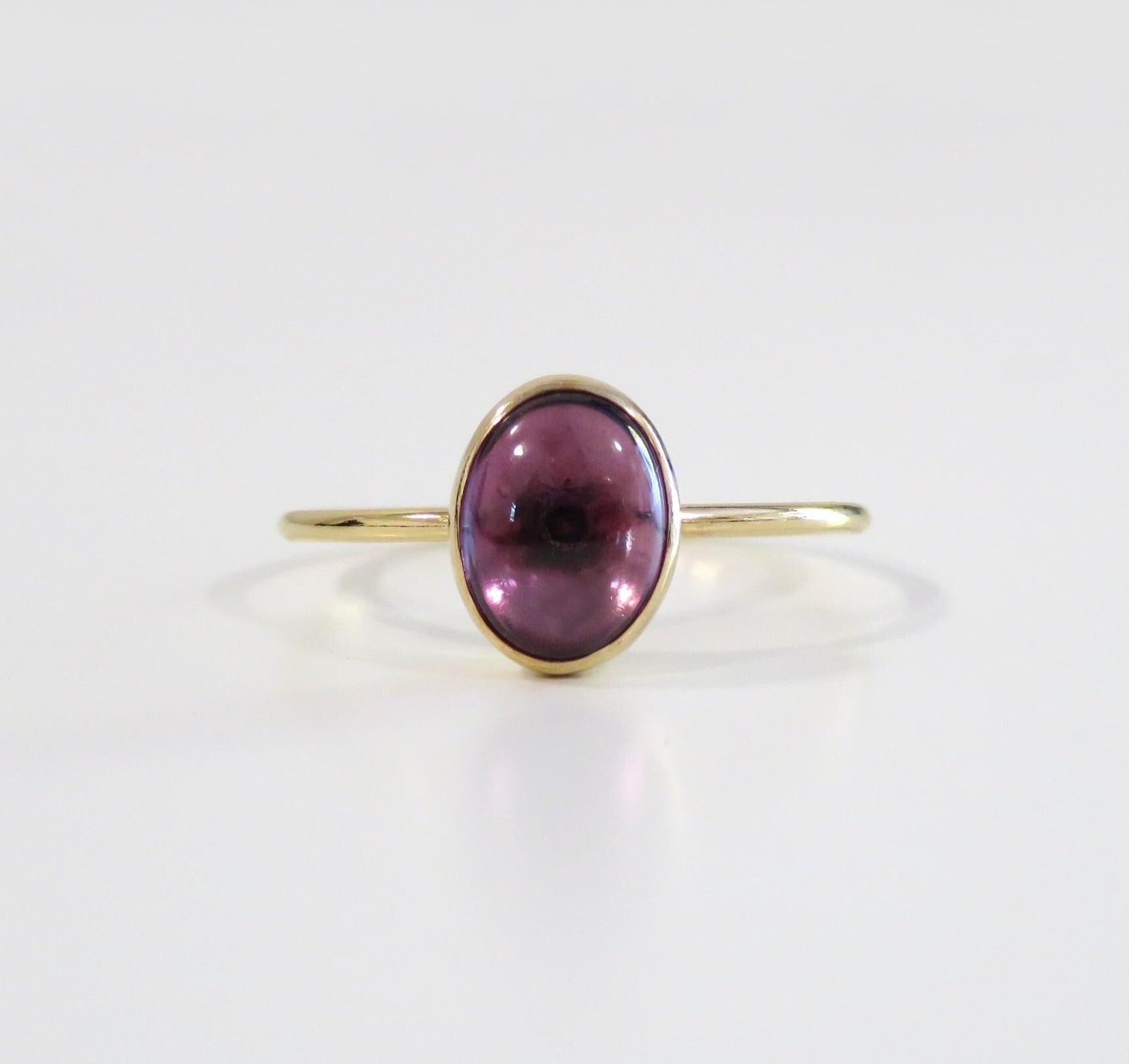 Gold ring with a purple gemstone on a white background