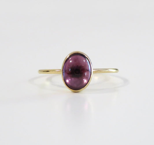 Gold ring with a purple gemstone on a white background